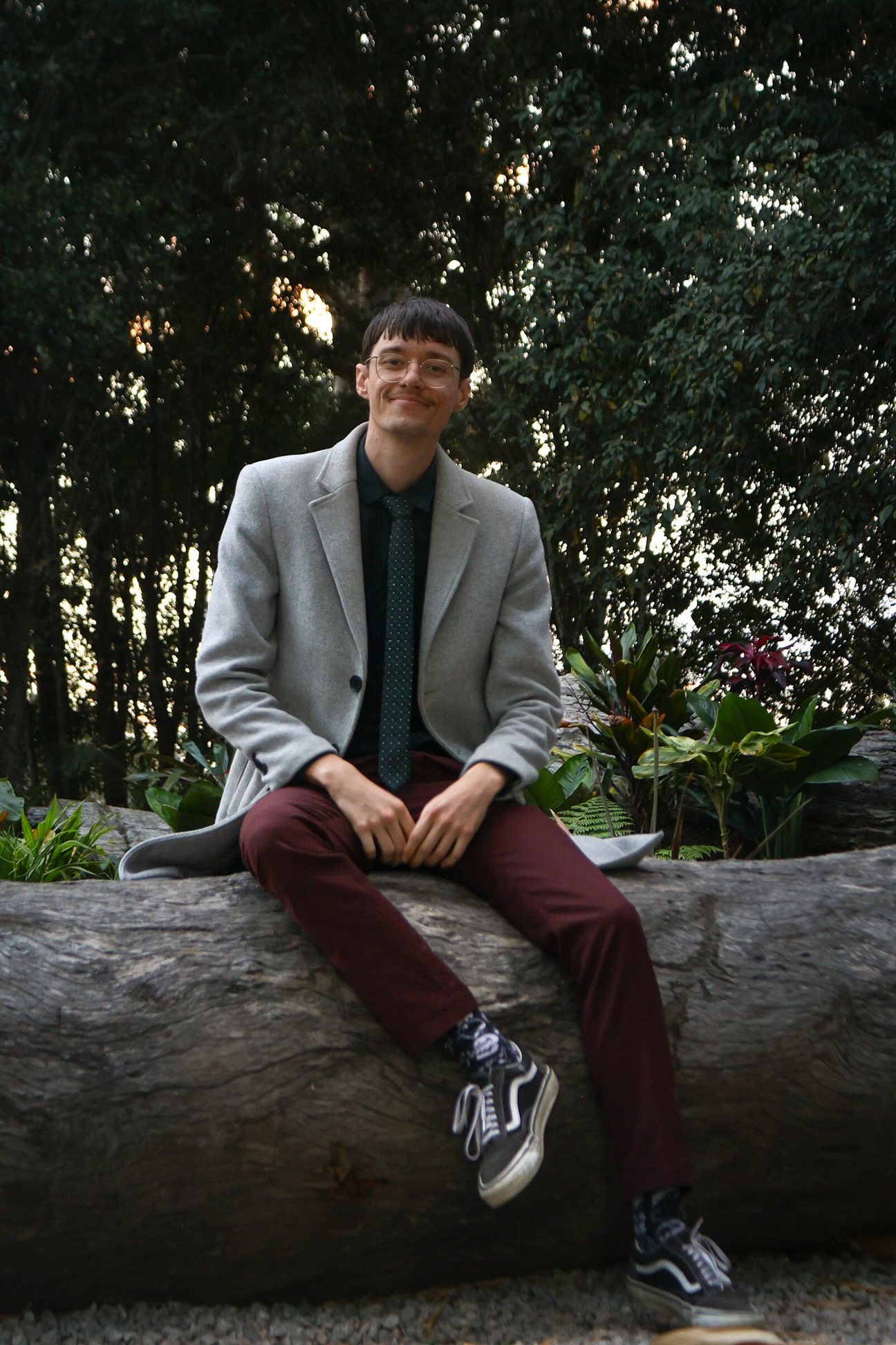 Photo of Andrew sitting on a log with a natural Queensland backgroud.